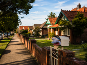 Overflowing suburban letterbox beside a quiet Sydney footpath on a calm morning.